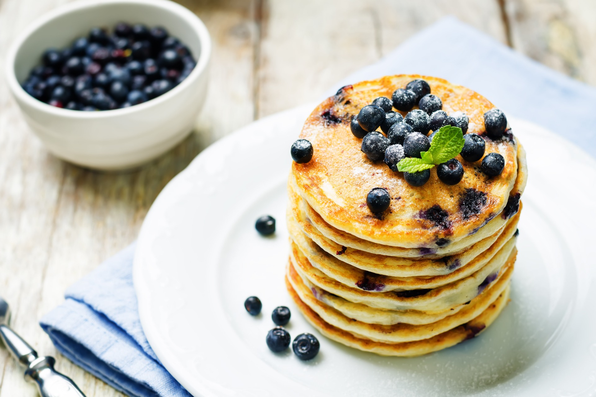 This is a photo of a stack of pancakes topped with blueberries.